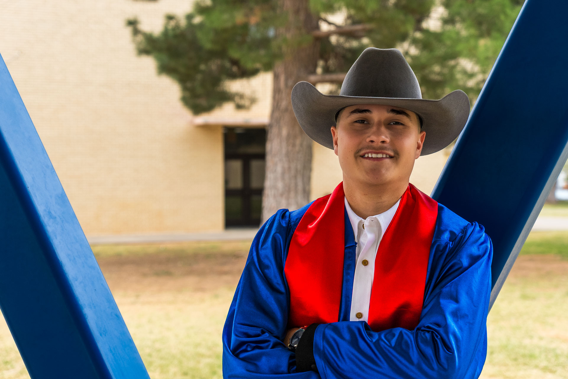 Aldo Cortez with arms crossed and cowboy hat in amphitheater 