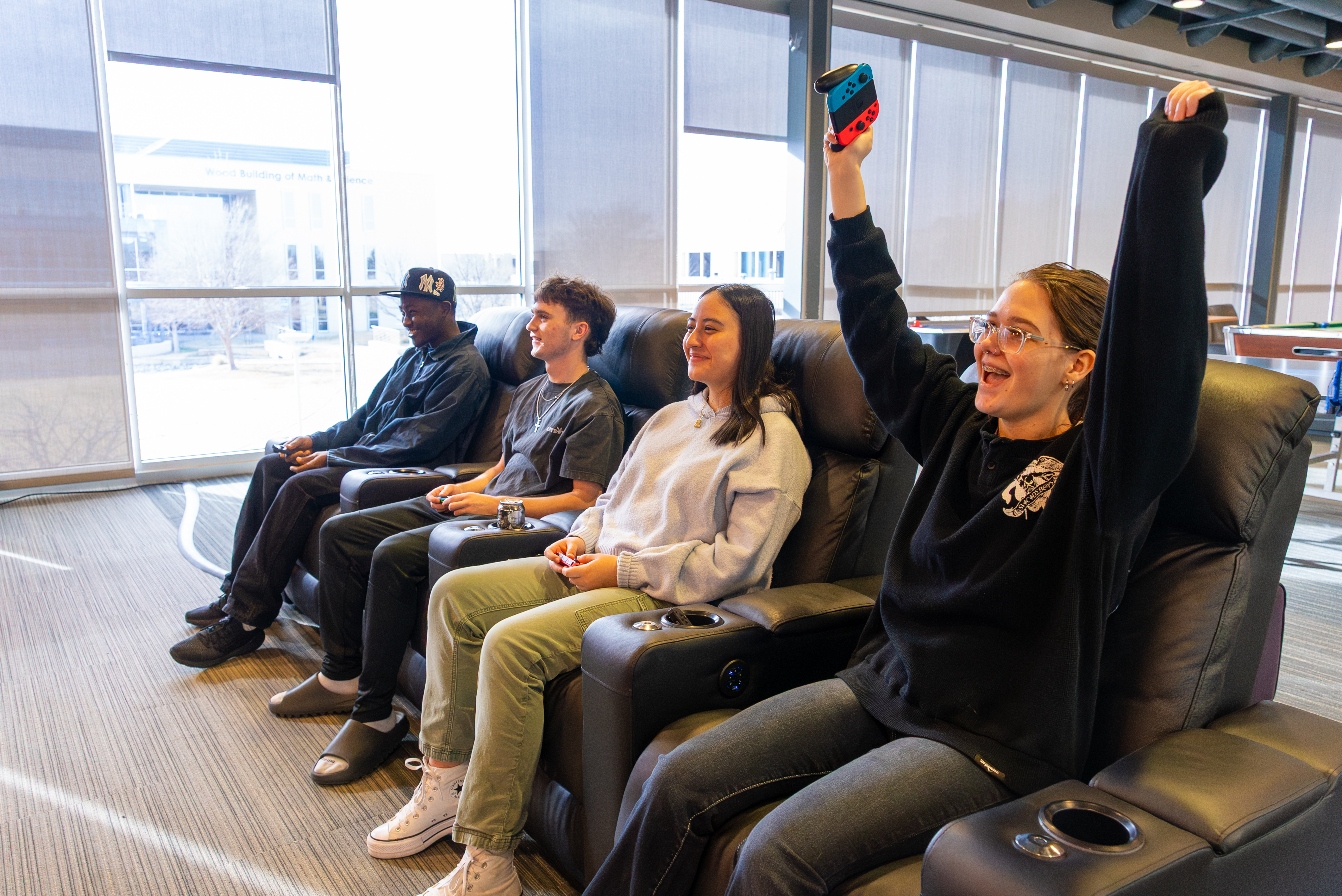 Student cheering as they win the round in a video game they're playing with their friends.