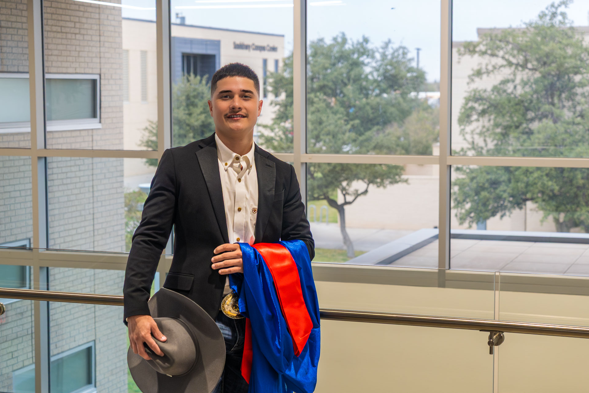 Aldo Cortez holding his graduation gown and hat