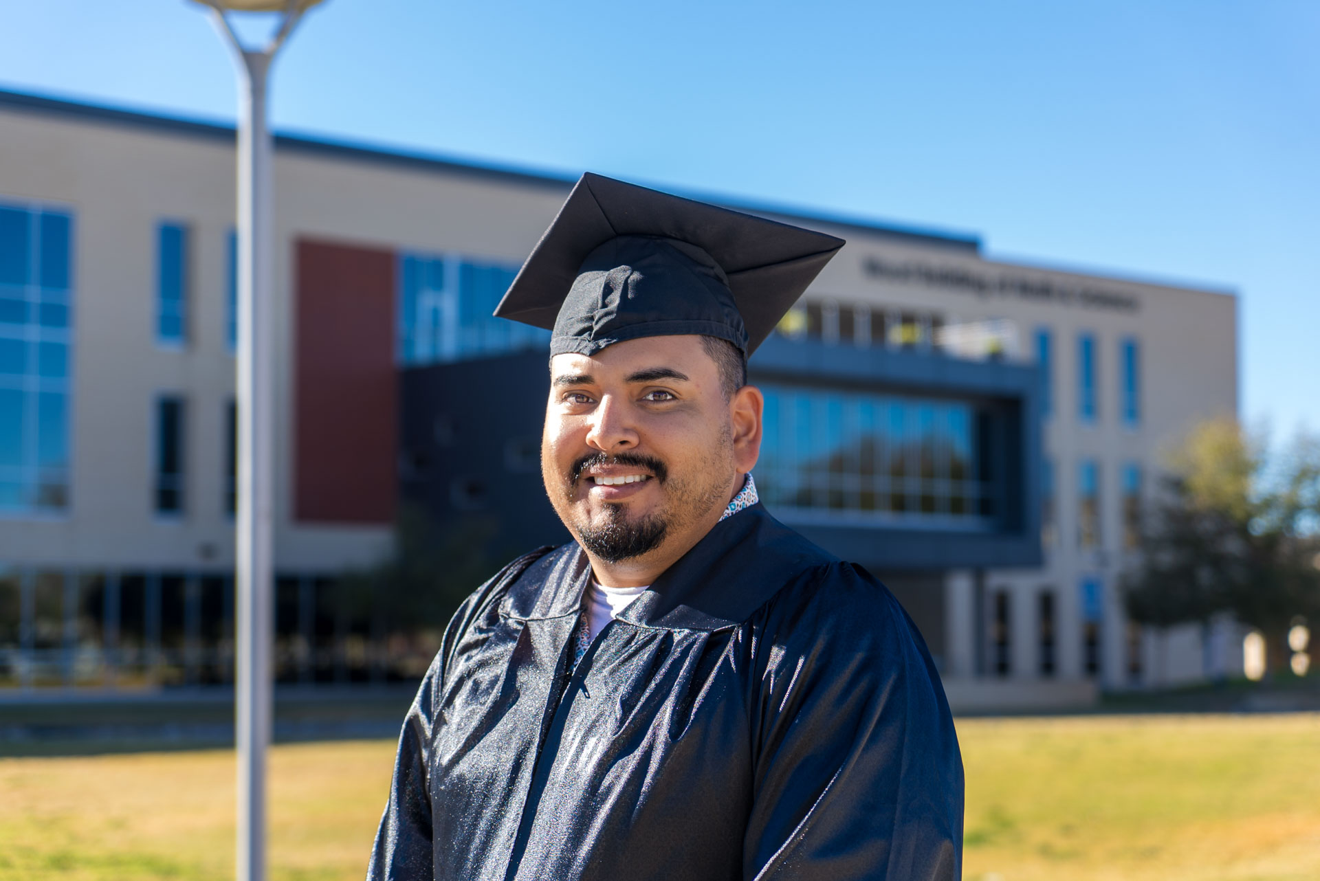 Luis smiling in front of building