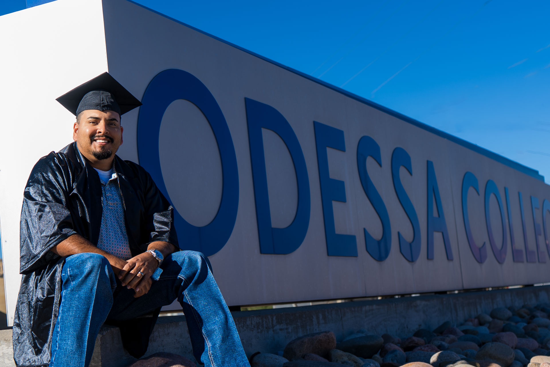 Luis Sigala sitting next to OC sign