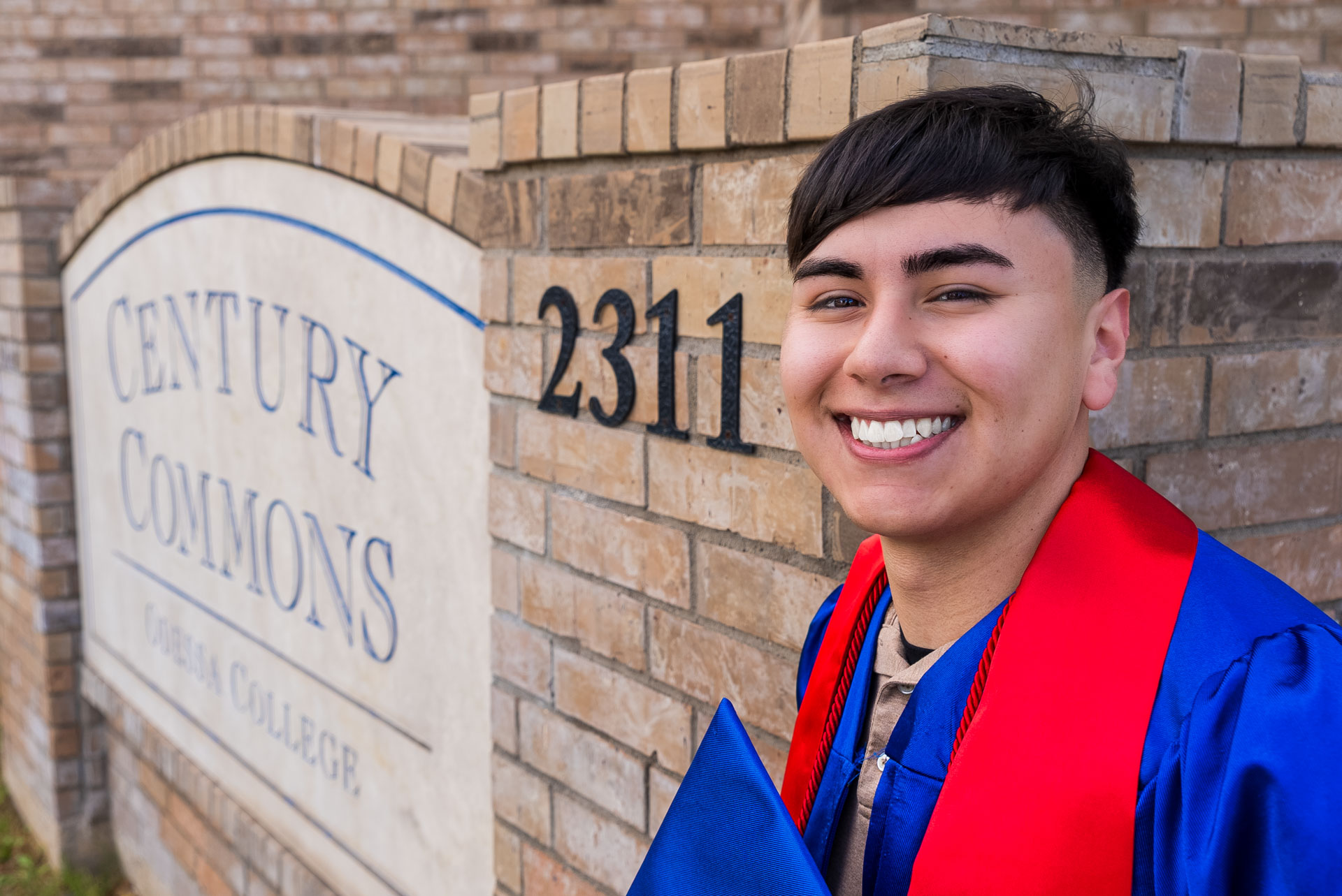 Raul Barrera smiling next to dorms sign