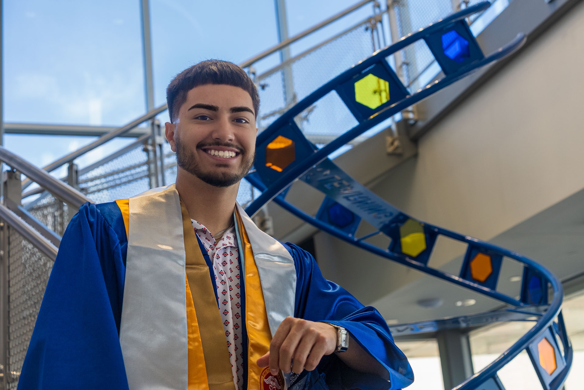Luis Munoz smiling with a DNA statue behind him
