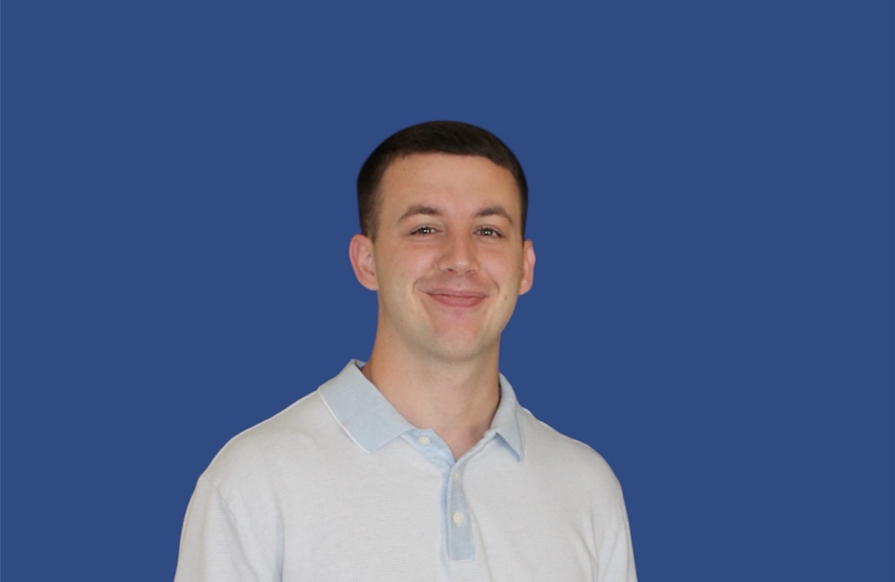 Man with light blue shirt in front of blue background